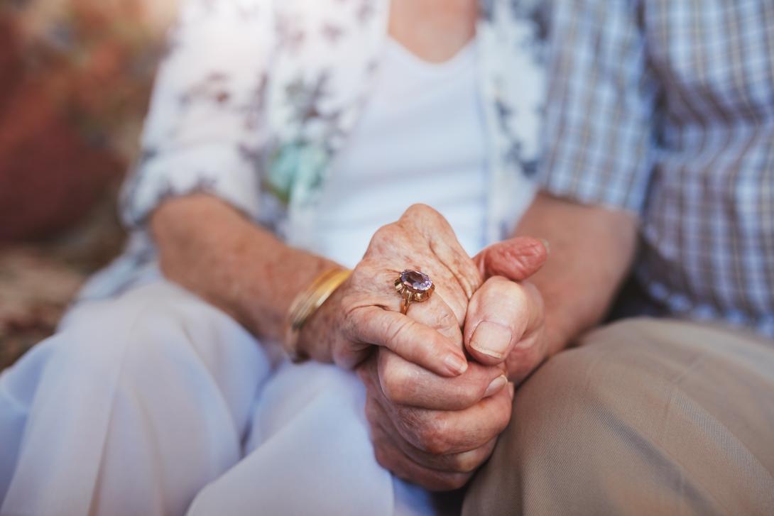Oudere mensen die samen zitten en handen vasthouden