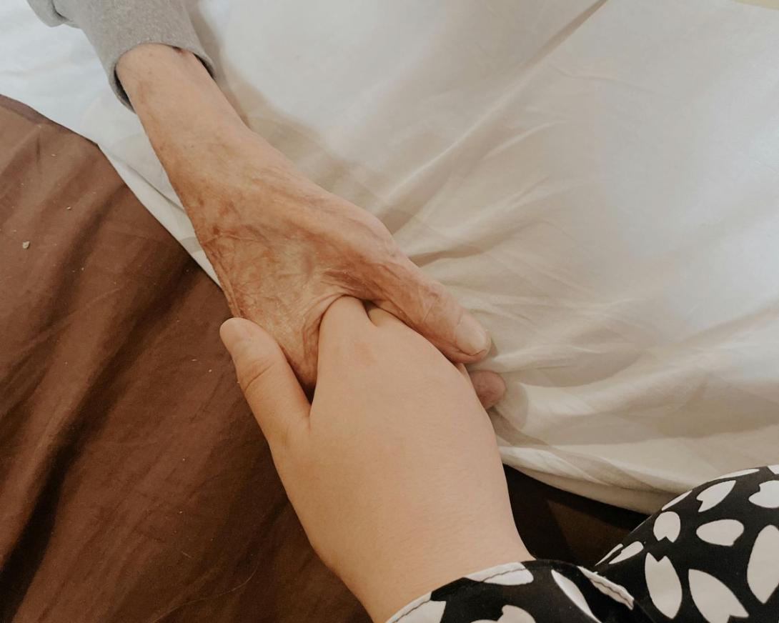 hand van volwassenen houdt hand van oudere zorgbehoevende vast