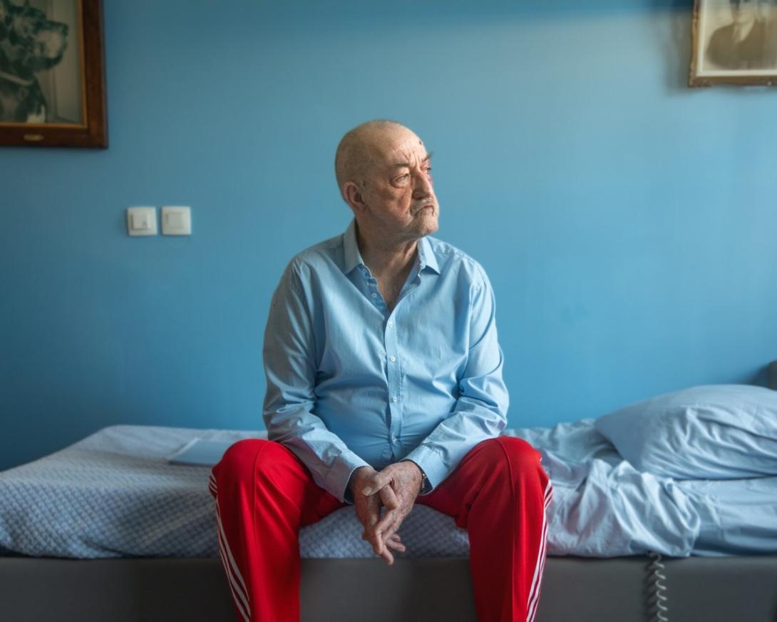Personage Horst zit op bed starend door raam 