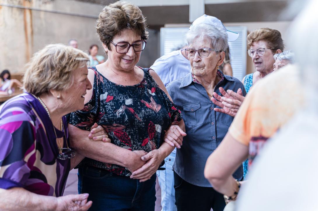 vrouw van middelbare leeftijd loopt arm in arm met twee oudere vrouwen